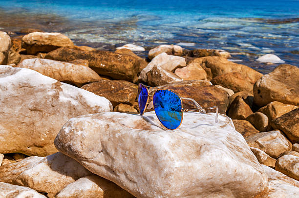 istock Sunglasses blue aviator on the beach rocks 627014766