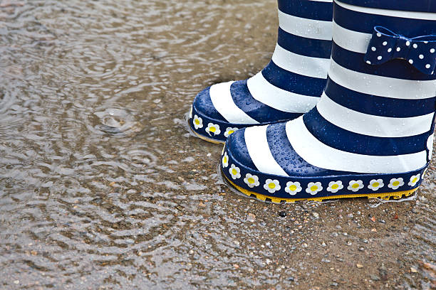 Unknown child with wellies or rain boots and puddle stock photo