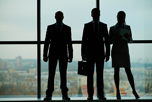 Silhouettes of three business people standing in a row