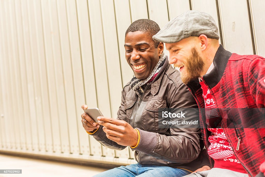 Happy Gay Men Couple Looking at a Mobile Smart Phone Two happy gay men looking at a mobile smart phone in Dublin Ireland Friendship Stock Photo