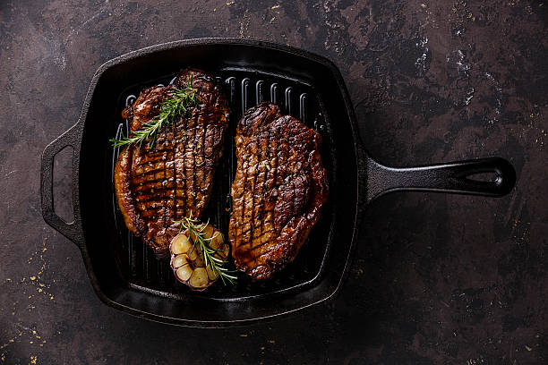 Grilled Steak on frying pan Grilled Black Angus Steak Striploin on frying cast iron Grill pan on dark background skillet cooking pan photos stock pictures, royalty-free photos & images