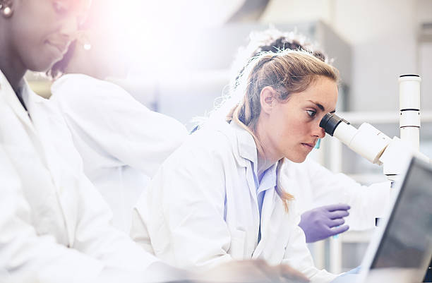 scientist looking through the microscope - laboratory pharmacy medicine research imagens e fotografias de stock