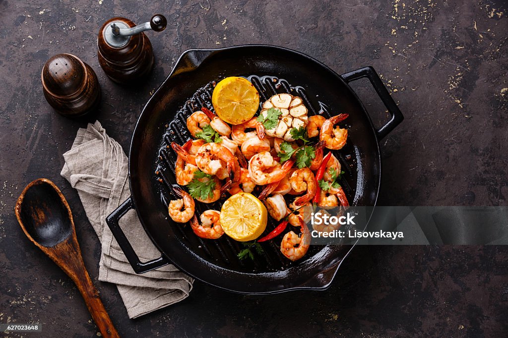 Prawns roasted on frying pan Prawns Shrimps roasted on frying grill pan with lemon and garlic on dark background Shrimp - Seafood Stock Photo