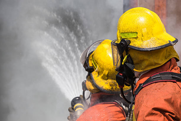 istock two firefighter in helmet and oxygen mask spraying water 627029248
