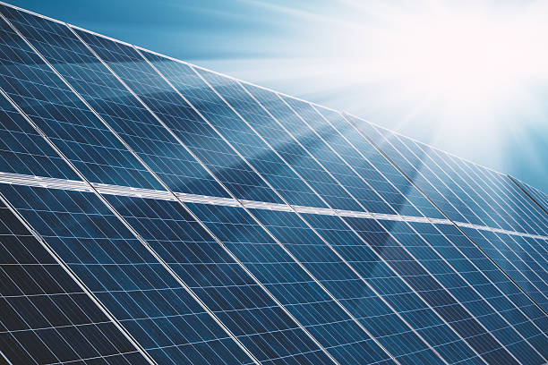 paneles de plantas de energía solar con rayos solares y cielo azul - solar power station fotografías e imágenes de stock