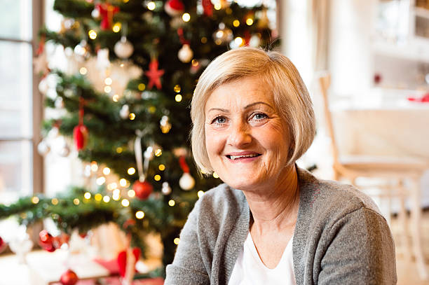 istock Senior woman in front of illuminated Christmas tree. 627032218