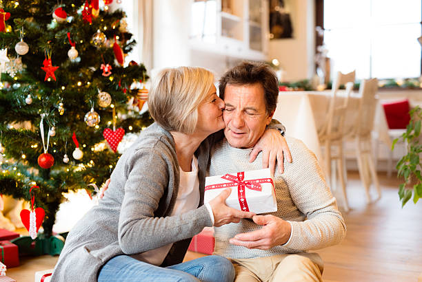 istock Senior couple in front of Christmas tree with presents. 627032408