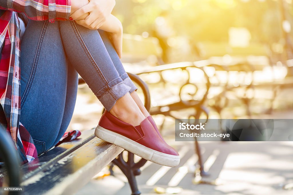 Sad teenage girl sitting on the park bench Teenage Girls Stock Photo