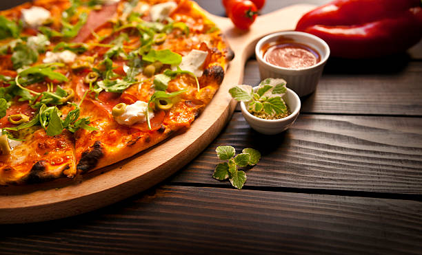 Rustic pizza with salami, mozzarella, olives and basil on wooden table