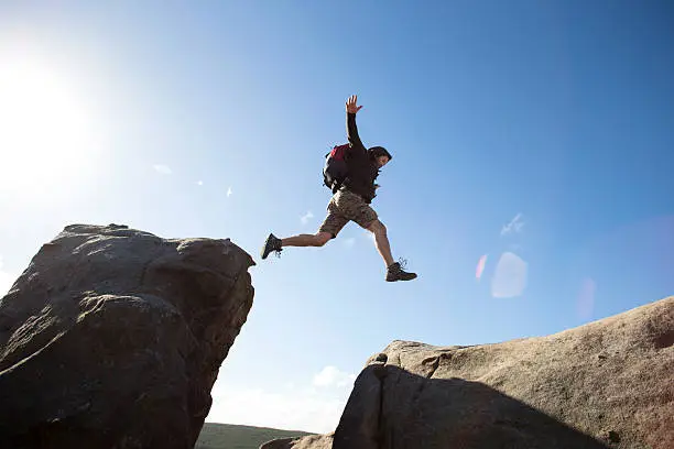 Man jumping between rocks on a cliff.