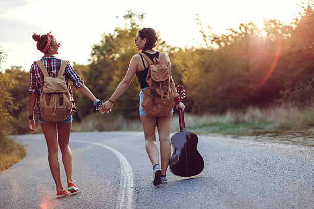 Beautiful hipsters in field at sunset walking throw nature