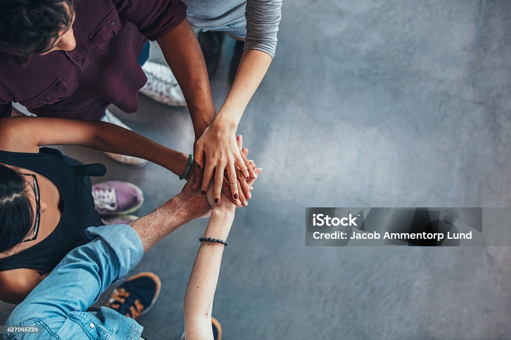 Group Of young people stacking their hands Top view image of group of young people putting their hands together. Friends with stack of hands showing unity. Teamwork Stock Photo