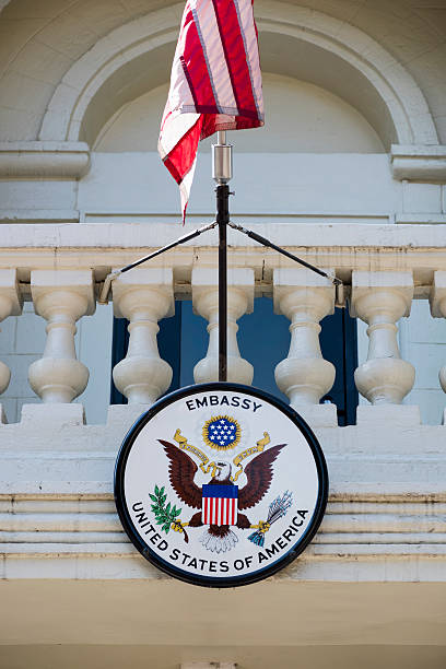 American embassy seal and U.S. flag in Moldova Chisinau, Moldova - September 11, 2016: An American flag and U.S. embassy seal hang outside the American embassy in Chisinau, Moldova. embassy photos stock pictures, royalty-free photos & images