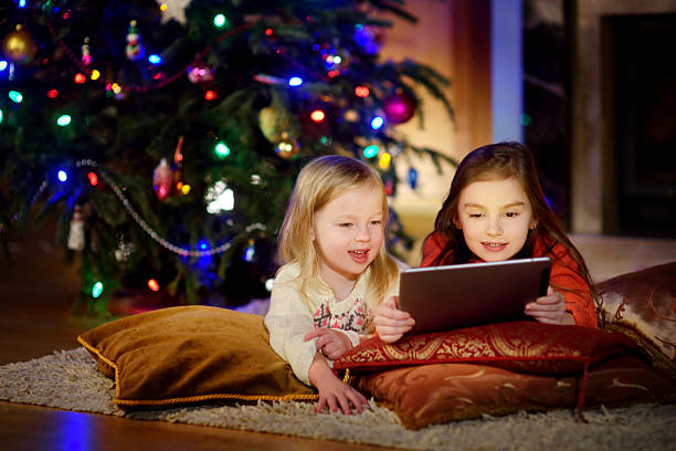 istock Two cute little sisters using tablet by fireplace on Christmas 627070700