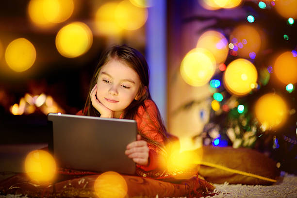 istock Adorable little girl using tablet pc by fireplace on Christmas 627071370