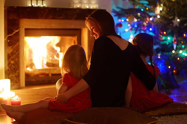 joven madre e hijas sala de estar con una chimenea de navidad - home decorating living room luxury fireplace fotografías e imágenes de stock