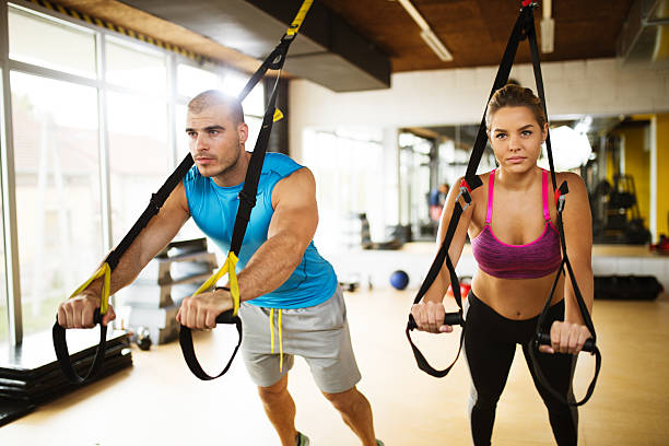 istock Couple doing arm exercises with suspension straps at gym. 627076370