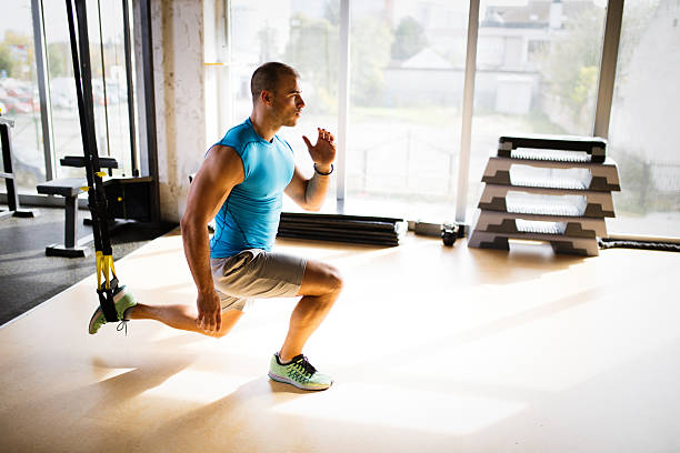 istock Man doing leg exercises with suspension straps at gym. 627076660