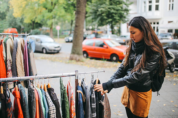 Vintage toned portrait of a young woman in Berlin, wearing a black leather jacket and a beige skirt, walking down the street in Berlin  Kreuzberg district in the late Autumn day, shopping on the street market. Street style, casual fashion concept.