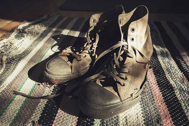 istock Old sneakers stand on knitted carpet 627088414