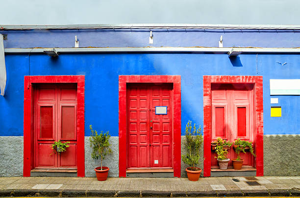 House with red doors in San Cristobal de La Laguna. Blue house with three red doors in the old Town of San Cristobal de La Laguna. Architectural detail of creative colorful house. Color blocks architecture background. Tenerife, Canary Islands spanish flower pots stock pictures, royalty-free photos & images