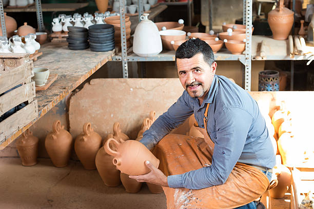 istock man potter holding ceramic vessels in atelier 627092618