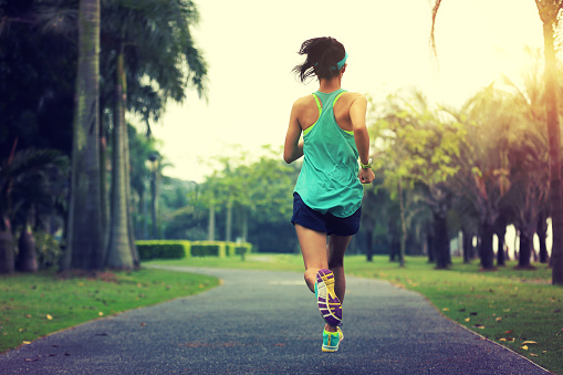 estilo de vida saludable joven deportista asiática mujer corriendo en el parque tropical photo