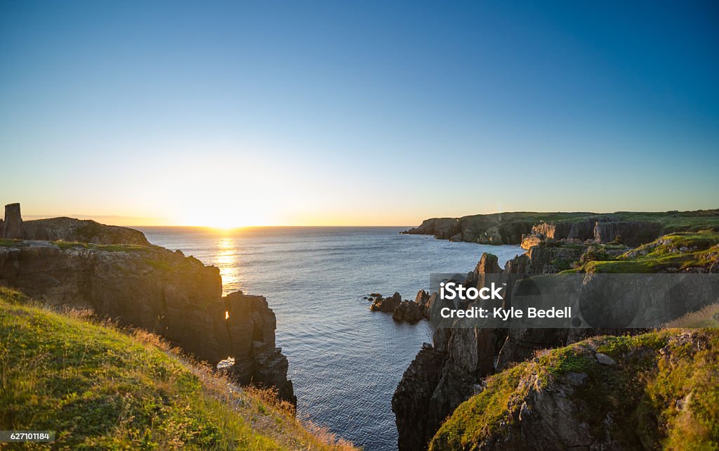 Dramatic sunrise cliffs at Cable John Cove Newfoundland. Dramatic sunrise on August morning.  Summer sun breaks  over the Atlantic ocean in Lancaster and Cable John Cove, Newfoundland, Canada.   Canada Stock Photo
