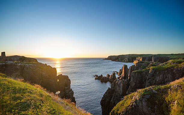 Dramatic sunrise cliffs at Cable John Cove Newfoundland. Dramatic sunrise on August morning.  Summer sun breaks  over the Atlantic ocean in Lancaster and Cable John Cove, Newfoundland, Canada.   atlantic ocean stock pictures, royalty-free photos & images