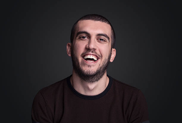 istock Portarit of young man laughing over black background, 627110536