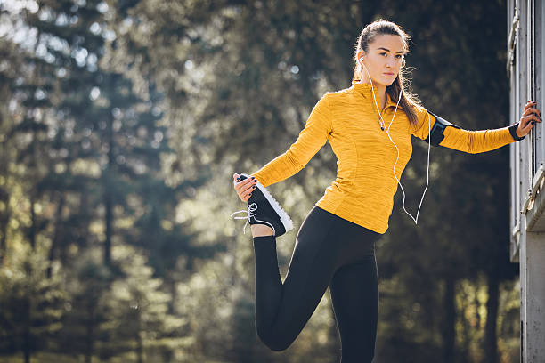 stretching prima di fare jogging  - jogging autumn young women women foto e immagini stock