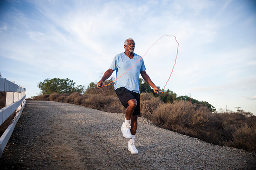 An attractive senior black man exercises outdoors by jumping rope