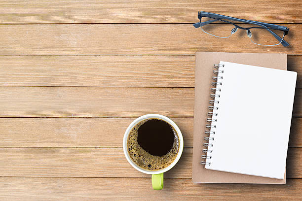 istock Notebook, glasses and cup of coffee on wood table 627147426