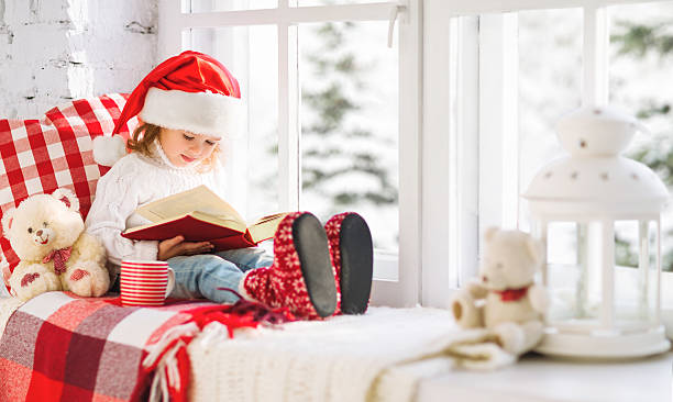 istock happy child reading a book while at a winter window 627164012