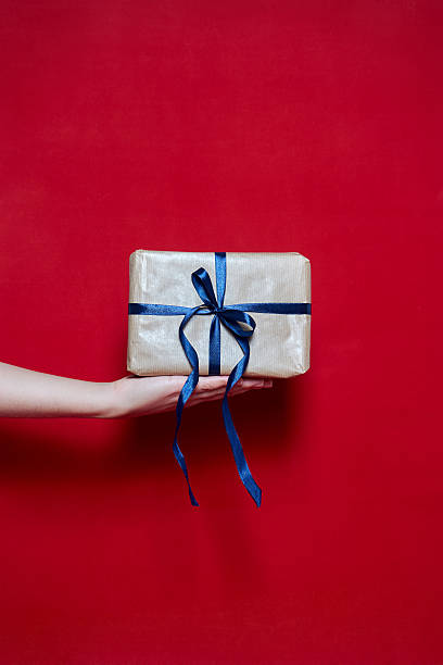 istock Womans Hand holding a box gift on red background 627169474