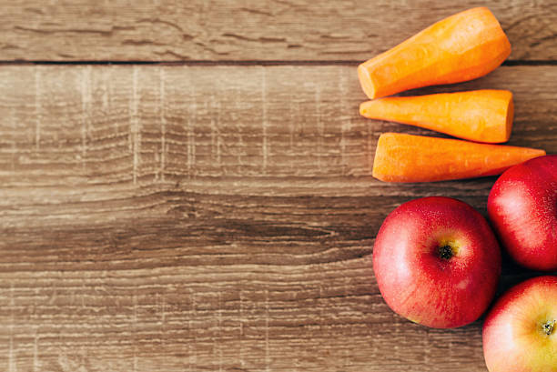 istock red apple and yellow carrots on the wooden table 627178182