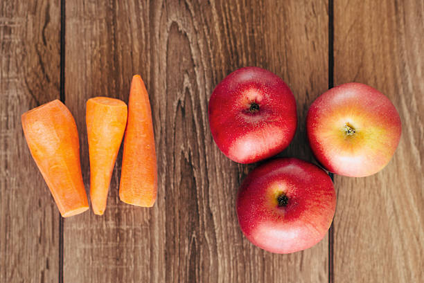 istock red apple and yellow carrots on the wooden table 627183596