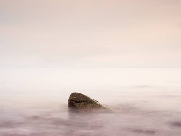 istock Romantic sea. Boulder stick out from smooth wavy sea. 627186052