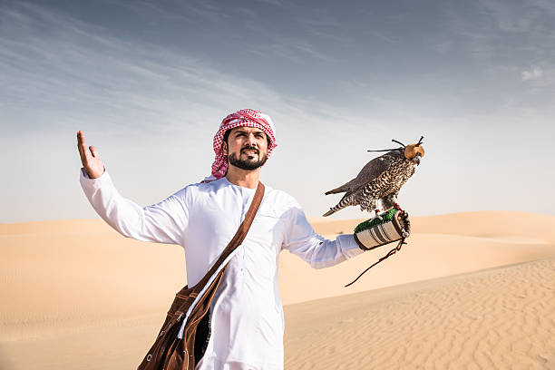 cheik arabe sur le désert tenant un faucon - middle eastern ethnicity sheik wealth men photos et images de collection