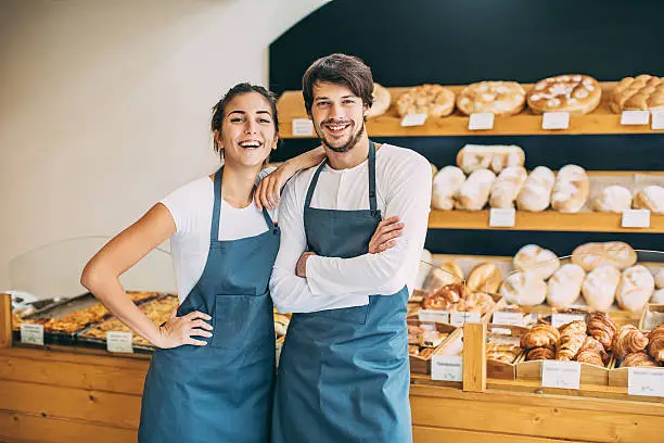 Couple of young bakers in their bread shop