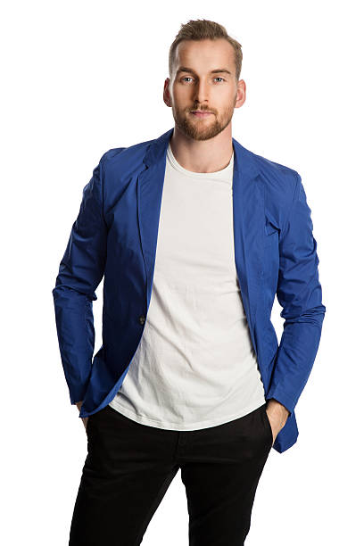 Fashionable male in blue jacket staring Trendy blonde man wearing a bright blue blazer and dark jeans, standing against a white background smiling towards camera. blazer jacket photos stock pictures, royalty-free photos & images
