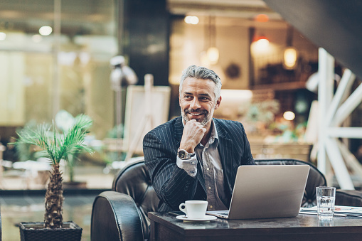 Smiling mature businessman working in the lobby of a modern business building, with copy space.