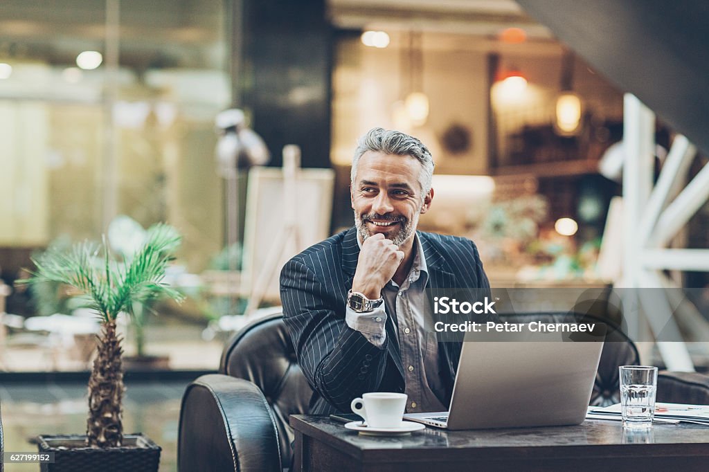Mature businessman working in comfort Smiling mature businessman working in the lobby of a modern business building, with copy space. Businessman Stock Photo
