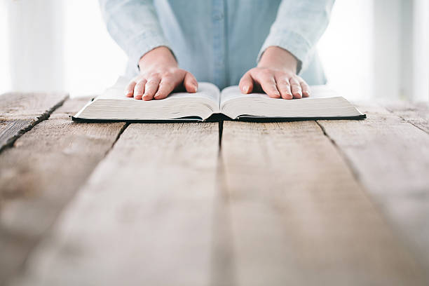 istock Woman reading and praying over Bible 627203660