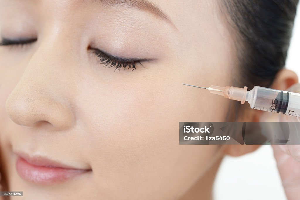Young woman gets beauty injection in her face Doctor makes a cosmetic injection in her face Adult Stock Photo