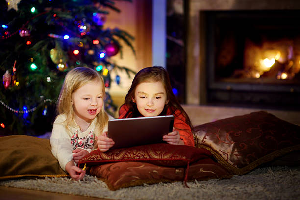 istock Two cute little sisters using tablet by fireplace on Christmas 627217850