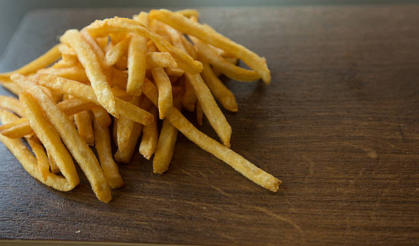 istock potato fry on wood isolated background 627225484