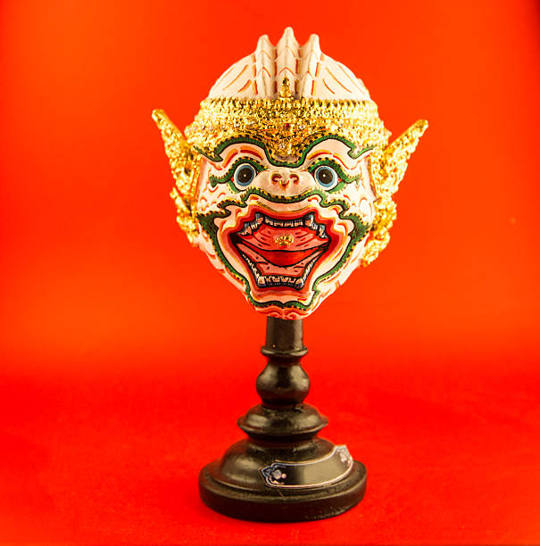 Colorful Chinese opera facial mask, painted human face, traditional theater expression decor on red wall, festive art design, Lunar New Year tradition.