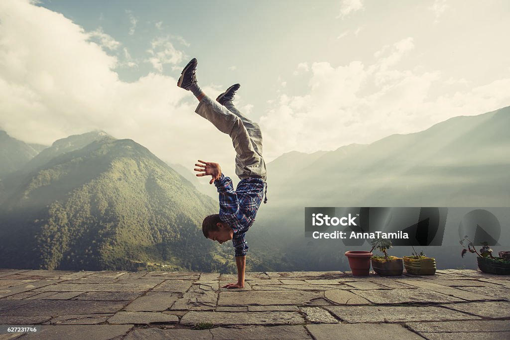 Young sporty man doing handstand exercise in beautiful mountain landscape Young sporty man doing handstand exercise in beautiful mountain landscape. Sports outdoor lifestyle Handstand Stock Photo