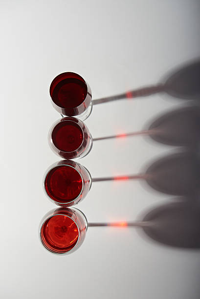 Line of glasses with red wine and shadows view from top